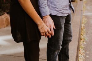 A man and woman holding hands on the street.