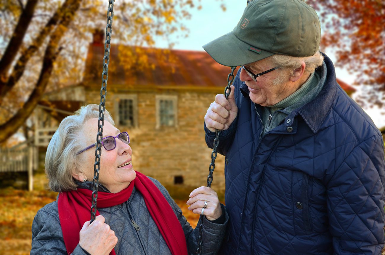 An older couple is swinging on a swing.