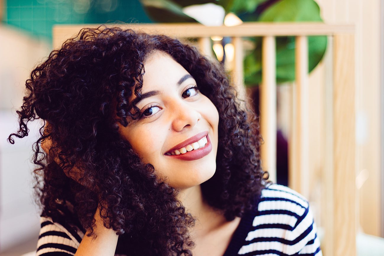 A woman with curly hair smiling at the camera.