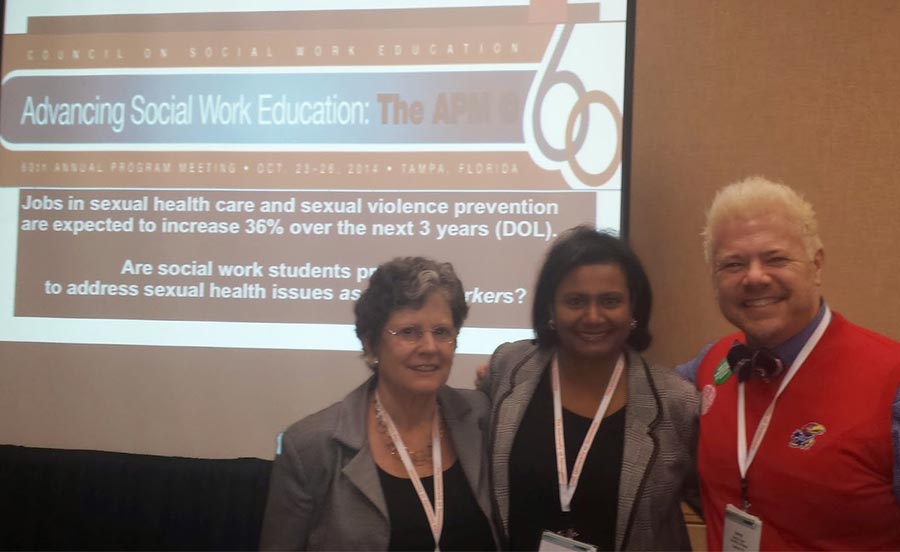 Three women standing in front of a presentation.