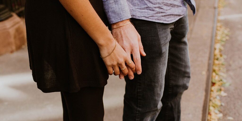 A man and woman holding hands on the street.